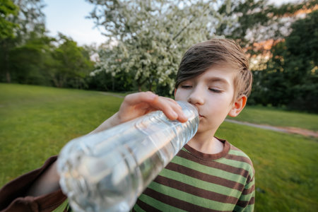 Boy drinking water from a bottle in the park. Healthy lifestyle.の写真素材