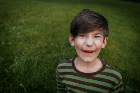 Portrait of a boy in a striped T-shirt on a background of green grassの写真素材