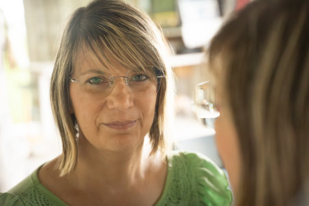 Mature woman and her daughter looking at each other in a cafeの写真素材