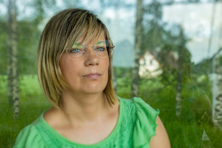 Portrait of a beautiful young woman with green blouse and glassesの写真素材