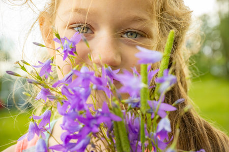 Little girl holding bouquet of blue bellflowers in summer parkの写真素材