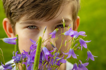 Little boy smelling a bouquet of bluebells in the parkの写真素材