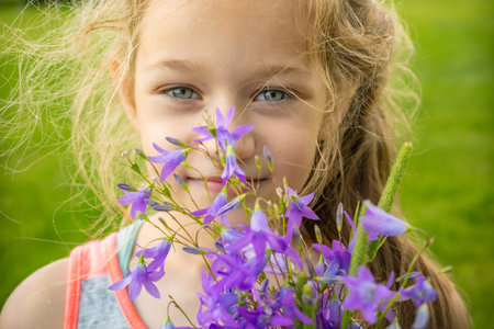 Cute little girl with a bouquet of bluebells outdoors.の写真素材