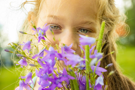 Little girl with bouquet of blue bellflowers in summer parkの写真素材
