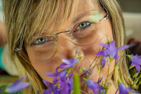 Woman with bluebells and green eye glasses looking at the cameraの写真素材