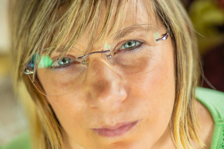 Close-up portrait of a woman with green eyes and glasses.の写真素材