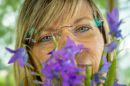 Mature woman with bluebells in the garden. Focus on eyes.の写真素材