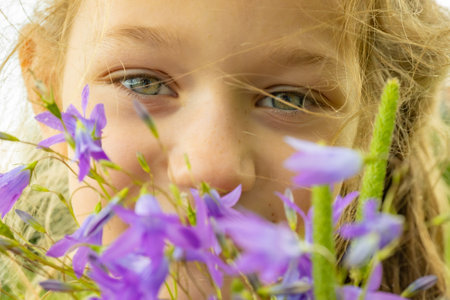 Little girl hiding behind wildflowers on a sunny summer day.の写真素材