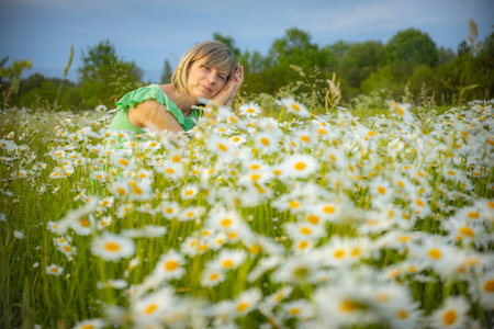 Little girl in camomile meadow on summer day. Selective focus.の写真素材