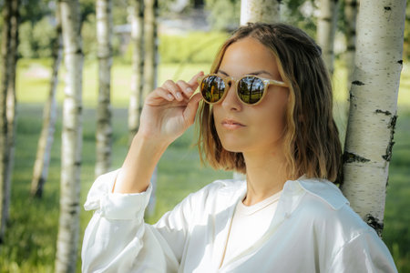 portrait of a young beautiful girl in a white shirt and sunglassesの写真素材