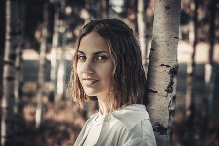 Beautiful young woman in the autumn forest. Photo in old color image styleの写真素材