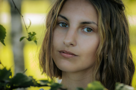 Portrait of a beautiful young girl on a background of green foliageの写真素材