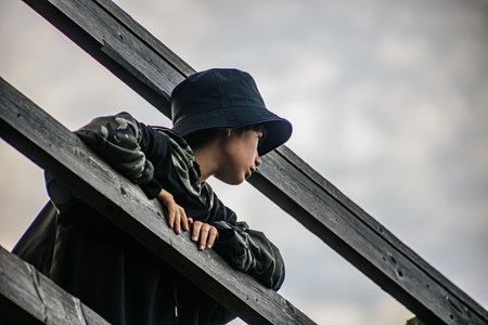 Portrait of a boy in a hat on a wooden staircase.の写真素材