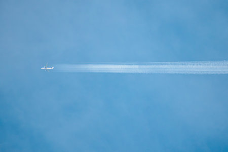Airplane in the blue sky with contrail in the air.の写真素材
