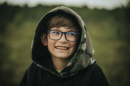 Portrait of a boy in a hooded jacket and glasses.の写真素材