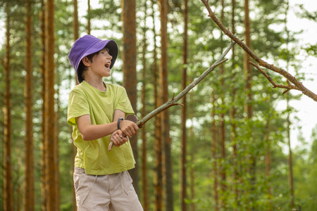 Young asian woman in purple hat and green shirt holding axe in forestの写真素材