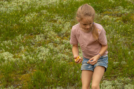 Little girl in a pink T-shirt and denim shorts on a green meadowの写真素材