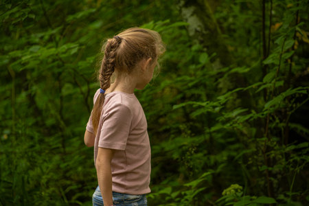 Little girl with pigtails standing in the woods. Back view.の写真素材