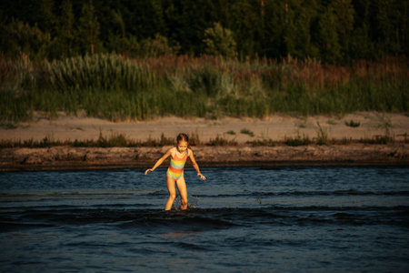 A little girl runs in the water on a hot summer day.の写真素材