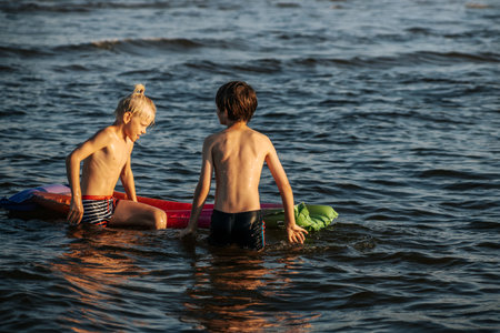 Two boys swim in the sea on an inflatable mattress. Summer vacation.の写真素材