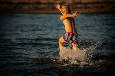 Cute little boy having fun on the beach. Happy child splashing in water.の写真素材