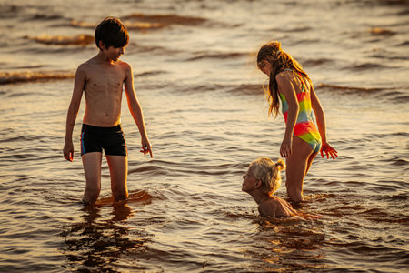 Mother, daughter and son playing in the water on the beach.の写真素材