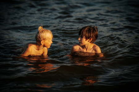 Two children swim in the sea at sunset. Selective focus.の写真素材