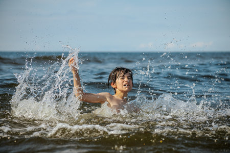 Cute little boy splashing in the sea on a sunny dayの写真素材