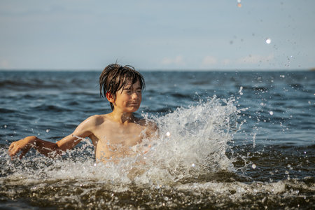 A boy splashes in the water on a sunny summer day.の写真素材