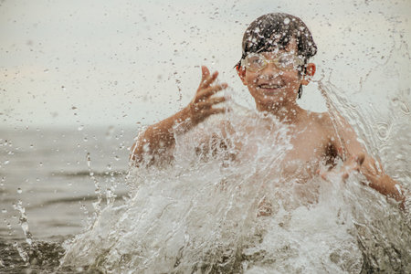 Portrait of a boy splashing water on the beach in summerの写真素材
