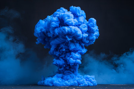 A dramatic burst of blue smoke expands against a solid black background, creating a striking contrast. The swirling, cloud like formation captures the dynamic motion and intensity of the explosion. AI generated.の素材