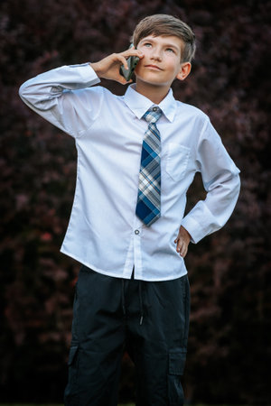 Portrait of a boy in a shirt and tie talking on the phone.の写真素材