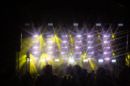 Stage lights and crowd of audience at a music festival. Concert lighting equipment.