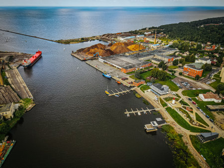 An aerial view of Salacgriva ship port, showcasing the marina with docks for small boats, a lighthouse, and surrounding greenery. The port area features well maintained pathwaysの写真素材
