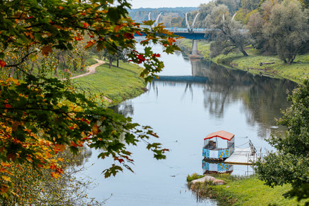 Autumn landscape with river, bridge and trees in the city parkの写真素材