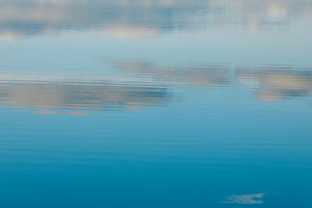 Reflection of the sky and clouds in the water of a lakeの写真素材
