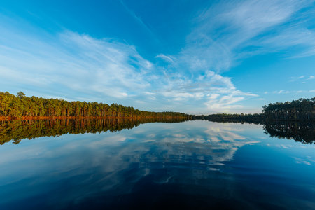 Reflection of the sky and clouds in the calm water of a lakeの写真素材