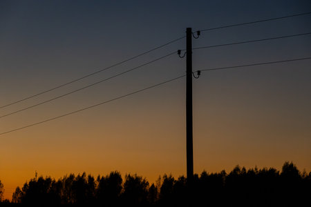 Silhouettes of power lines against the background of the setting sunの写真素材