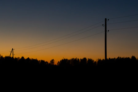 Silhouette of power lines on the background of the setting sunの写真素材
