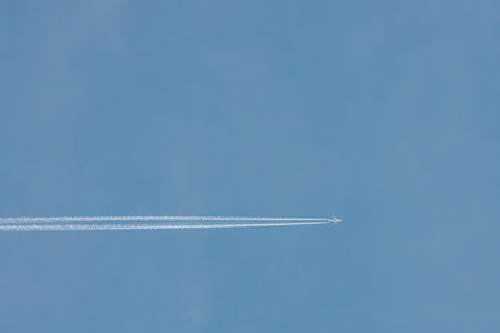 airplane in the blue sky with contrail, closeup of photo