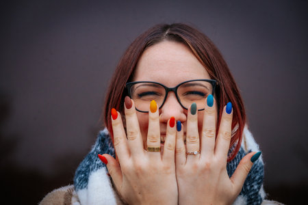 Portrait of a beautiful girl in glasses with red manicure.の写真素材