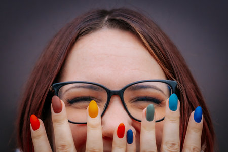 Portrait of a young woman with glasses and colored nail polish.の写真素材