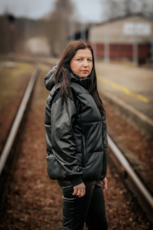 Young beautiful brunette woman in a black jacket on the railway stationの写真素材