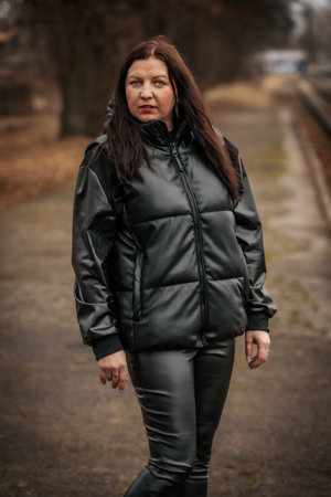 Young brunette woman in a black leather jacket posing on the railroad.の写真素材