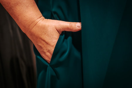 Close up of senior woman's hand pulling on a green dress.の写真素材
