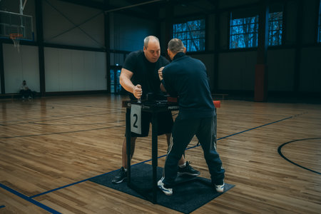 Side view of senior man doing push ups with personal trainer in gymのeditorial素材