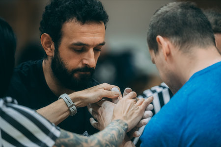 Handsome bearded man getting tattooed by a tattoo artist.のeditorial素材