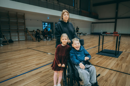 Young woman with her disabled children in a wheelchair in the gym.のeditorial素材