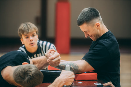 Two young men are training in a gym. They are sitting at the table and stretching.のeditorial素材