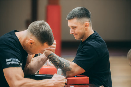 Young man with tattooes doing exercises with a trainer in a gymのeditorial素材